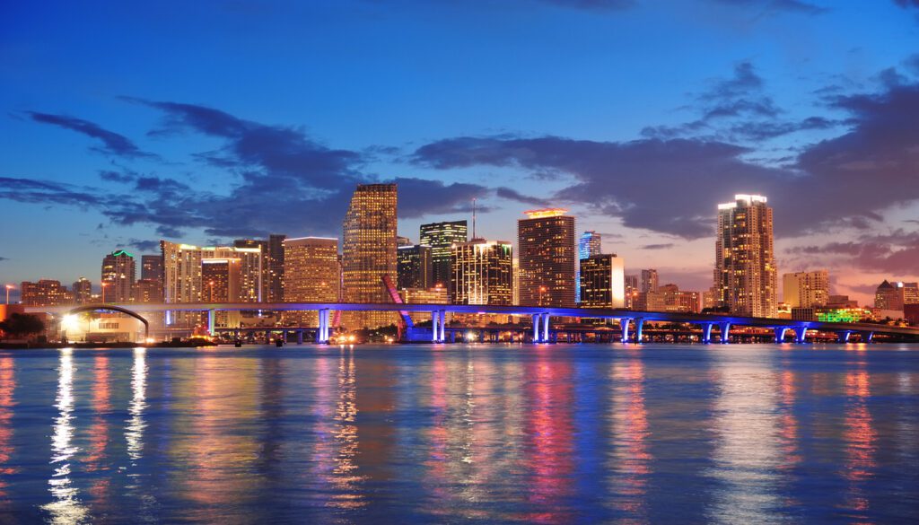 Vibrant Miami skyline at dusk with lit skyscrapers and bridge reflections for Boston to Miami flights