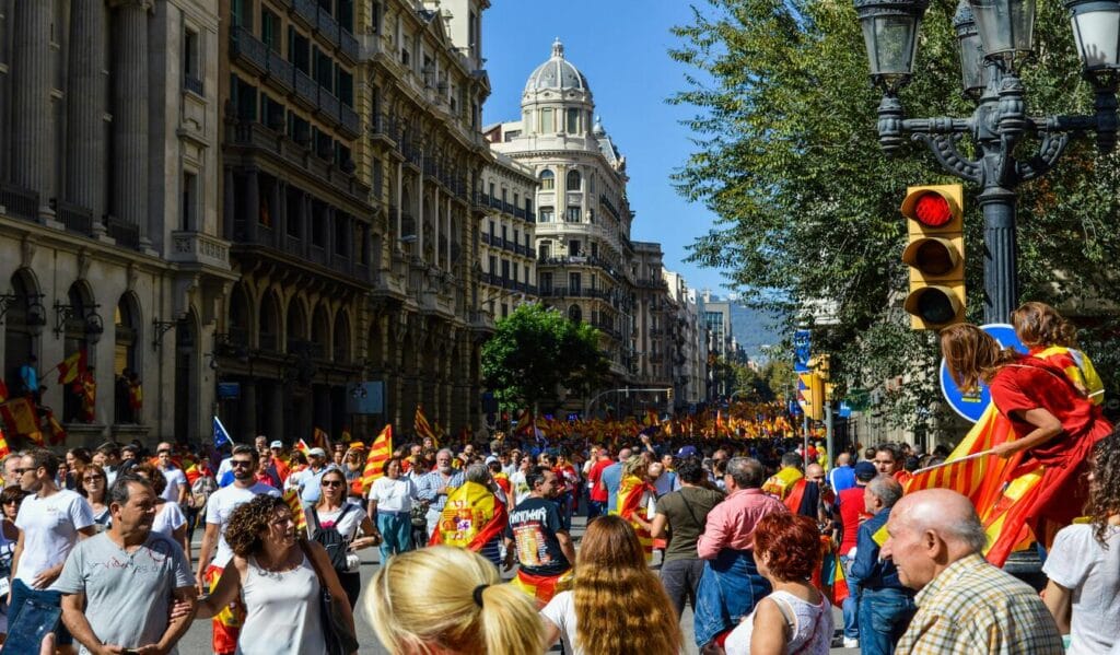 Catalan Festival Parade in Barcelona A vibrant street scene of a festival in Spain with people marching in the parade, waving Catalan flags in the heart of the city.