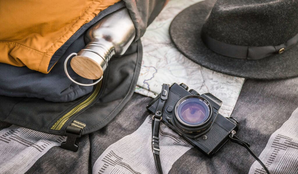 packing guide for Spain A still life shot featuring a camera, a water flask, a hat, a map, and a jacket, symbolizing essential travel items for a trip to Spain.