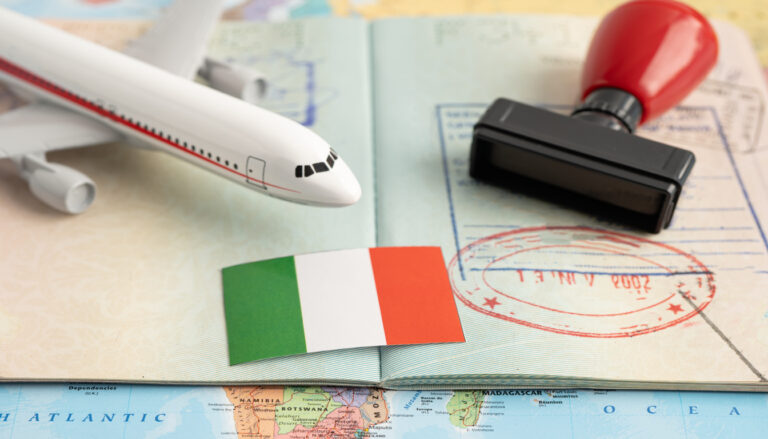 Model airplane, Italy flag, passport with stamp, and world map symbolizing flights to Venice, Italy