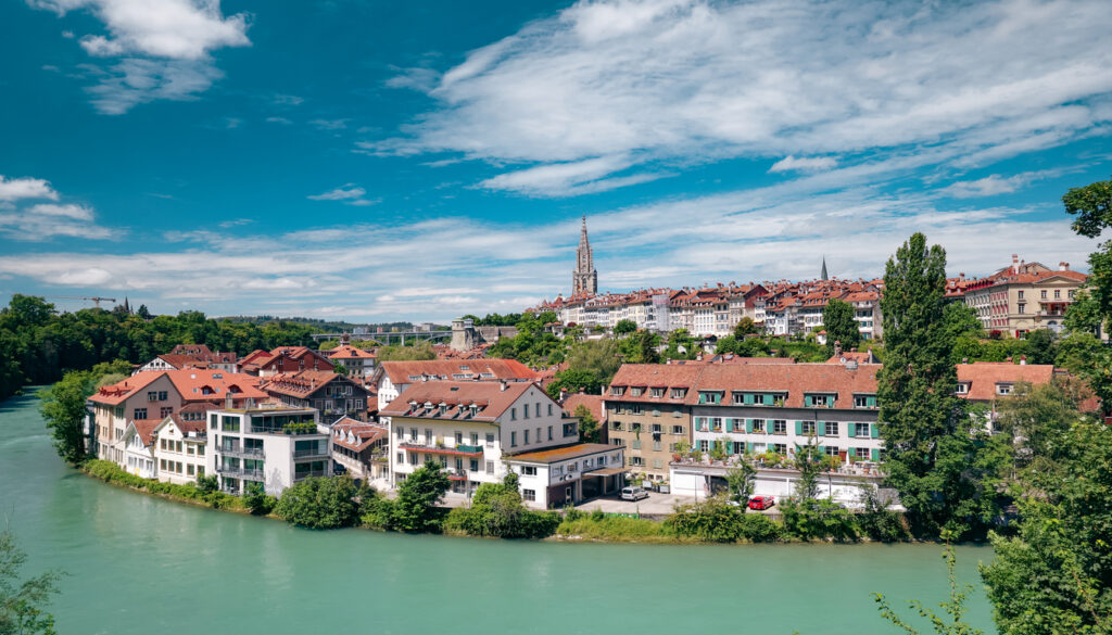 Scenic view of best Swiss city to visit with red-roofed buildings along turquoise river and historic cathedral spire