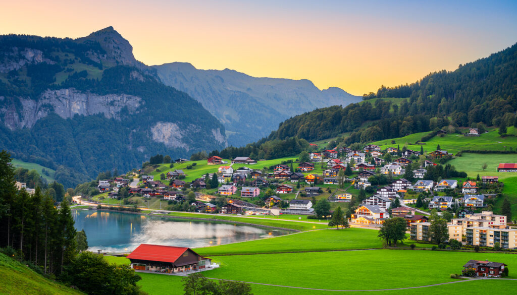 Charming Swiss village near Eugenisee lake surrounded by green hills — best time to travel to Switzerland.