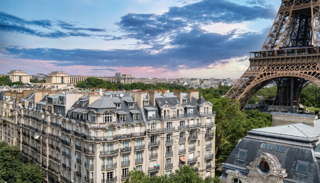 Hotels in Paris with Eiffel Tower view — charming Parisian buildings with the Eiffel Tower in the background at sunset.