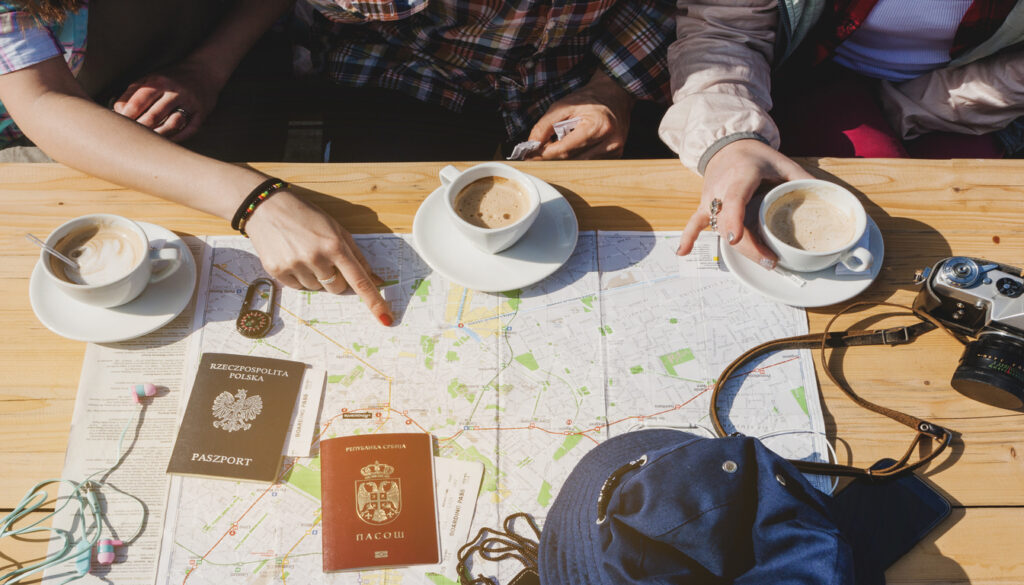 Group of travelers planning a trip with coffee cups, passports, and a map, ideal for planning the best time to travel to Switzerland.